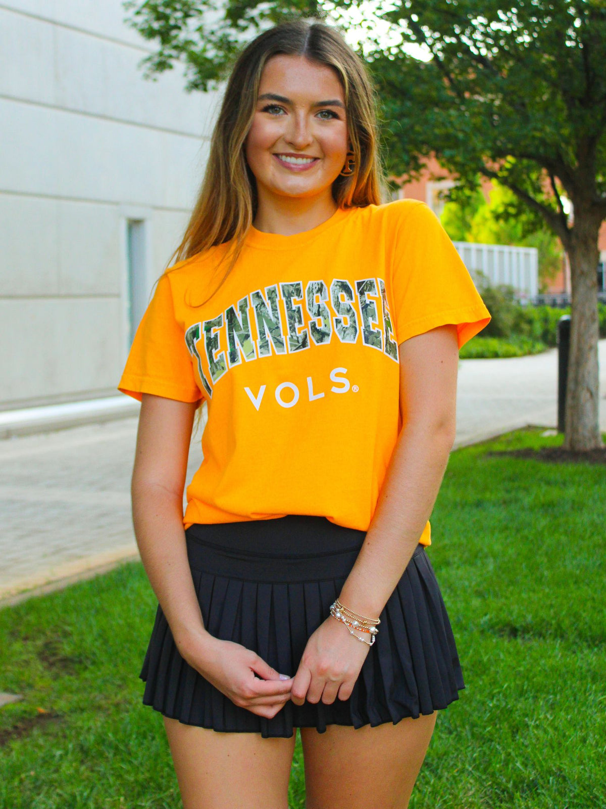 Woman wearing a bright orange 'Tennessee Vols' t-shirt outdoors.