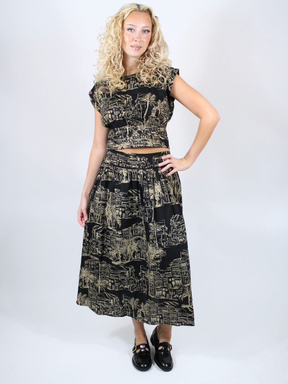 Woman wearing a black and gold patterned outfit on a white background
