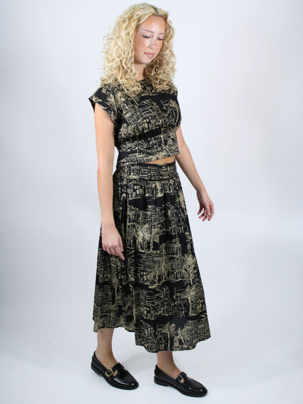 Woman wearing a black and gold patterned outfit on a white background