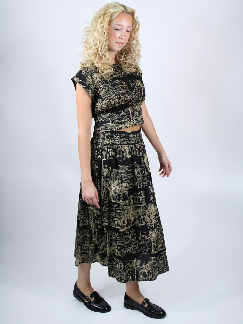 Woman wearing a black and gold patterned outfit on a white background