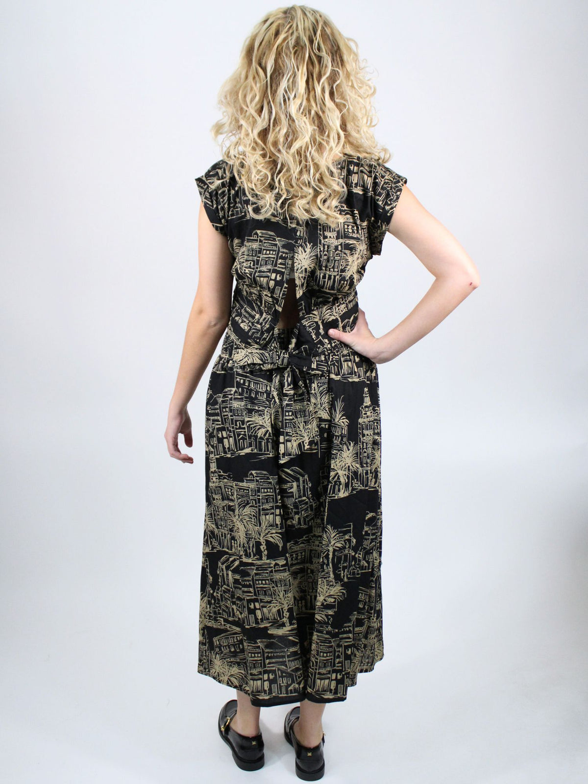 Woman wearing a black and gold patterned dress on a white background