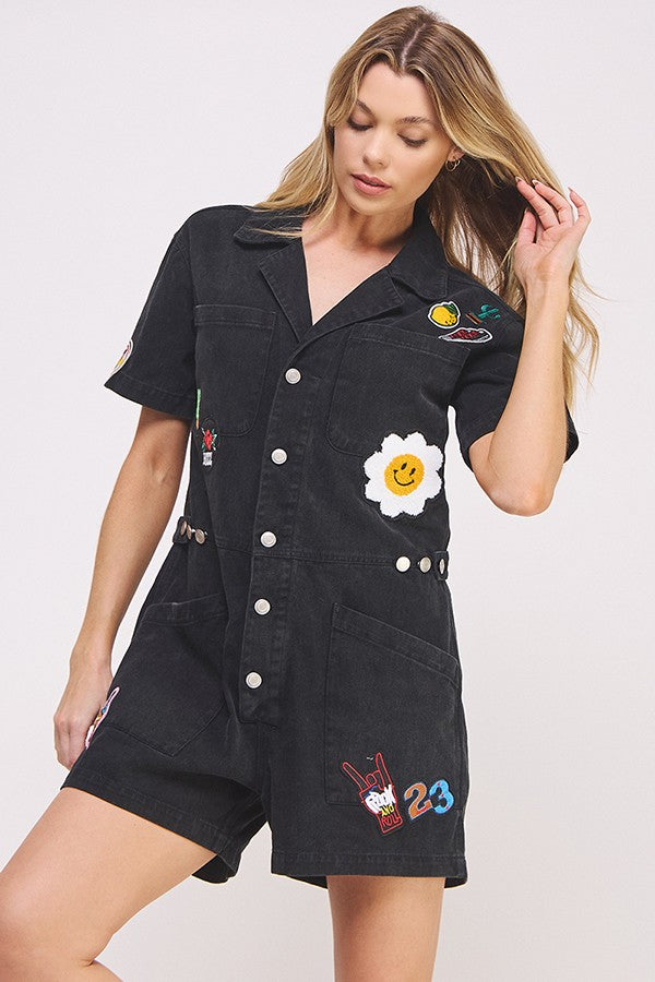 washed black short sleeve button down romper with patches-front