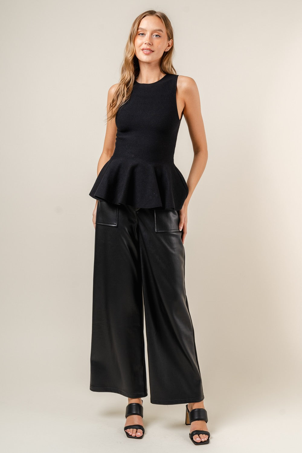 sleeveless peplum top in black-front