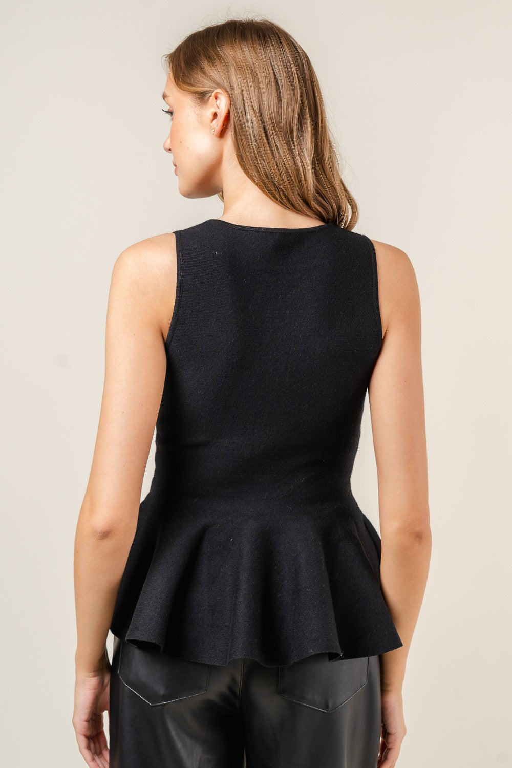 sleeveless peplum top in black-back