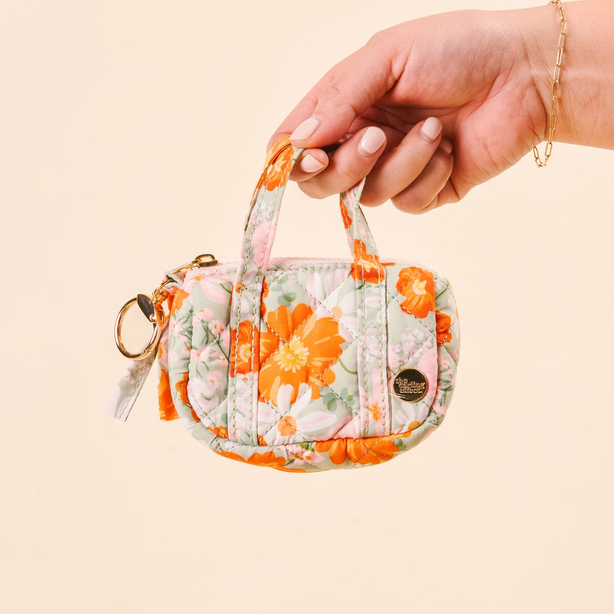 Hand holding Green Orange Pink Floral Mini Duffle Bag Bag Charm on Cream Background Darling Effect Itty Bitty Duffle Bag Charm Bouquet Beauty Sage