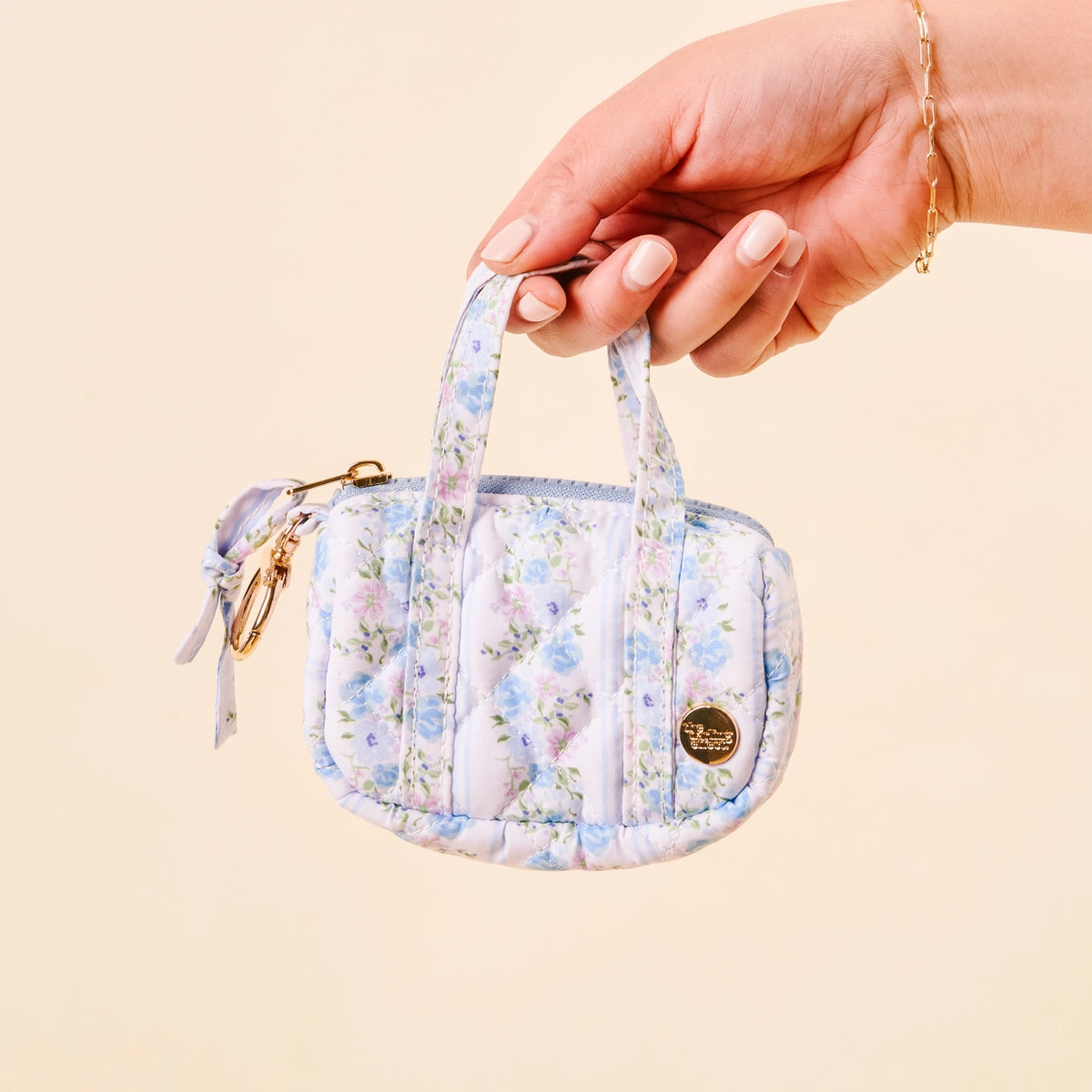 hand holding Light Blue White Purple Floral Mini Duffle Bag Bag Charm on Cream Background Darling Effect Itty Bitty Duffle Bag Charm Petal Parade Blue