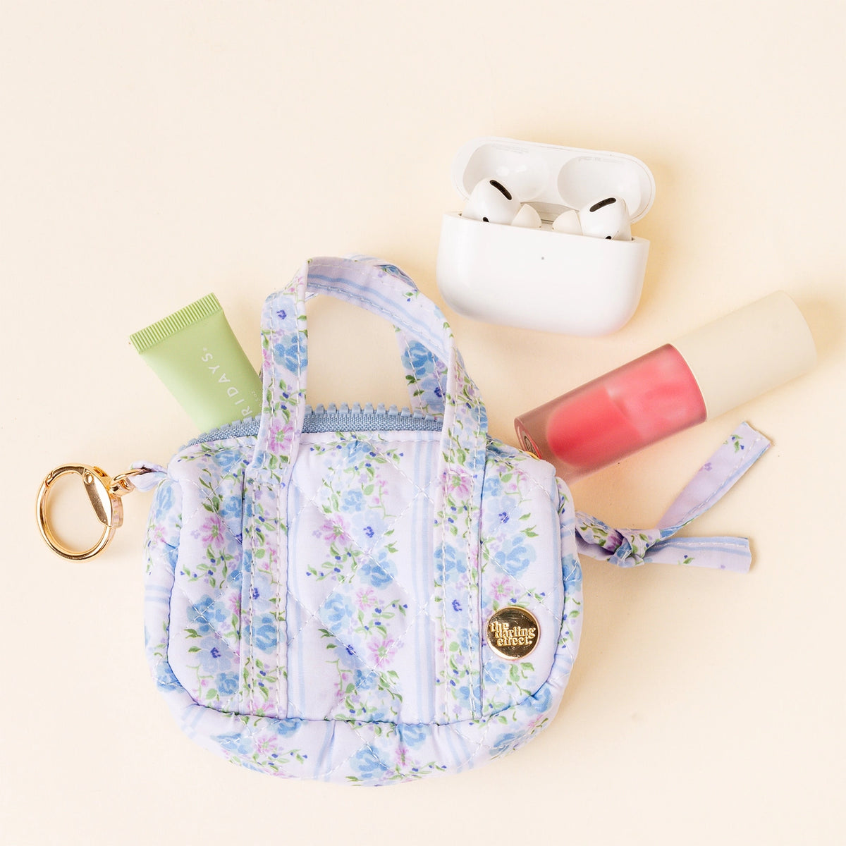 bag open with items around it Light Blue White Purple Floral Mini Duffle Bag Bag Charm on Cream Background Darling Effect Itty Bitty Duffle Bag Charm Petal Parade Blue