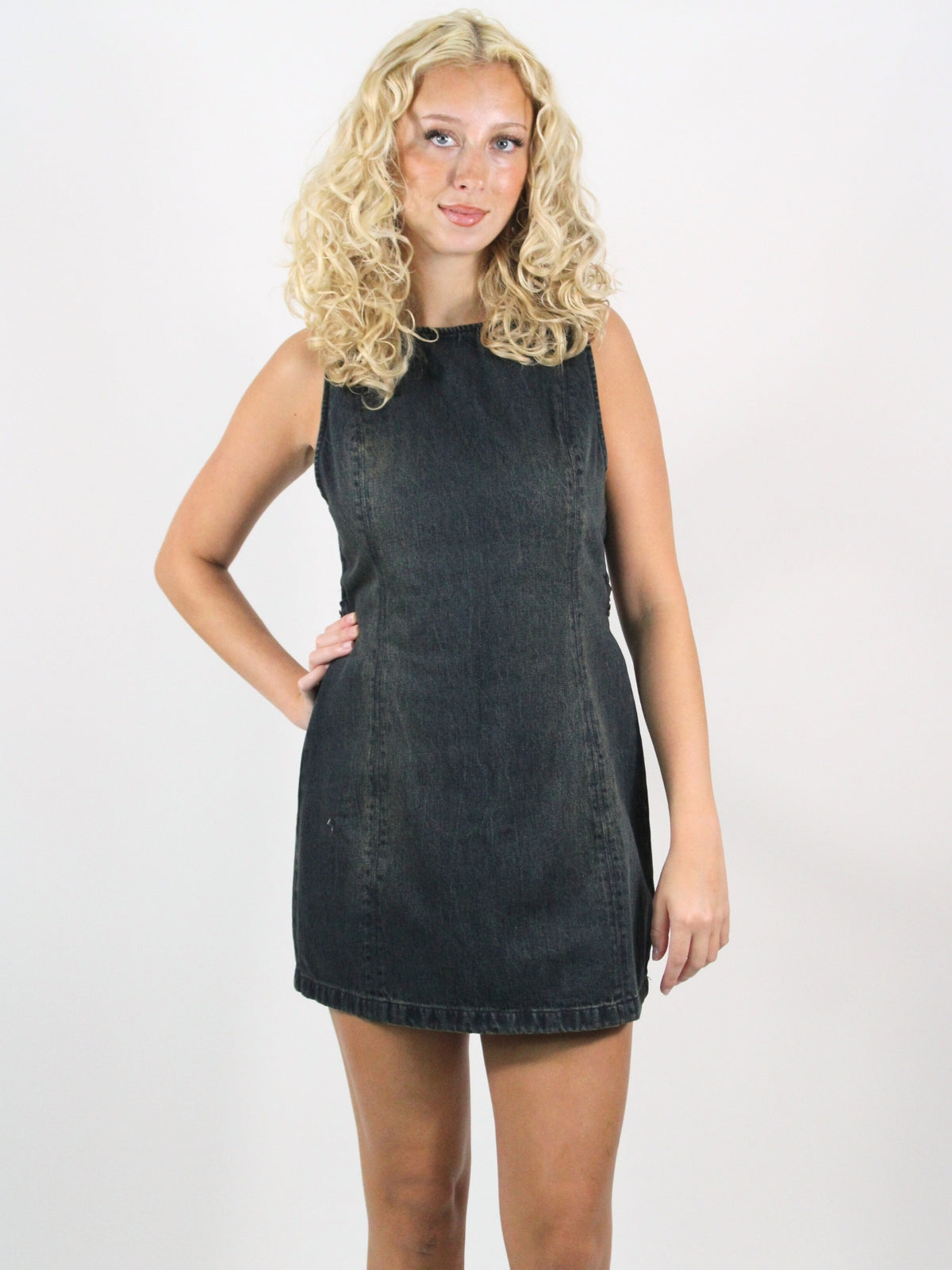 Woman wearing a black denim dress against a white background