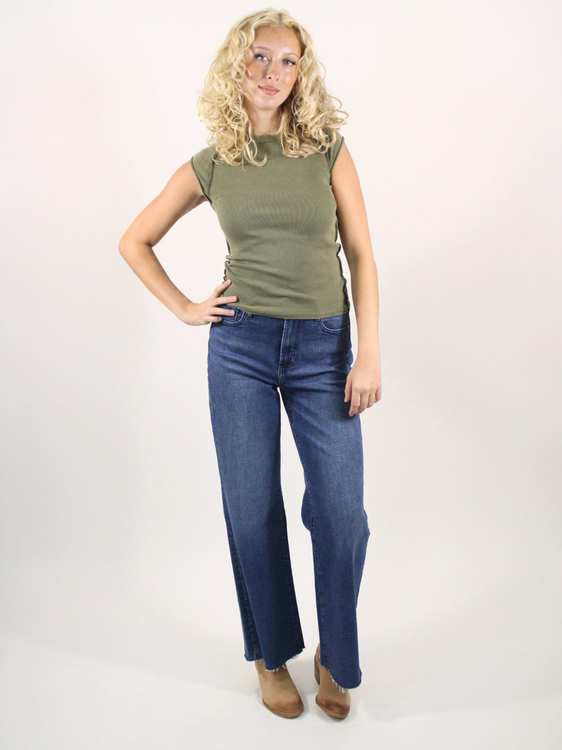 Woman wearing a green top and blue jeans on a white background