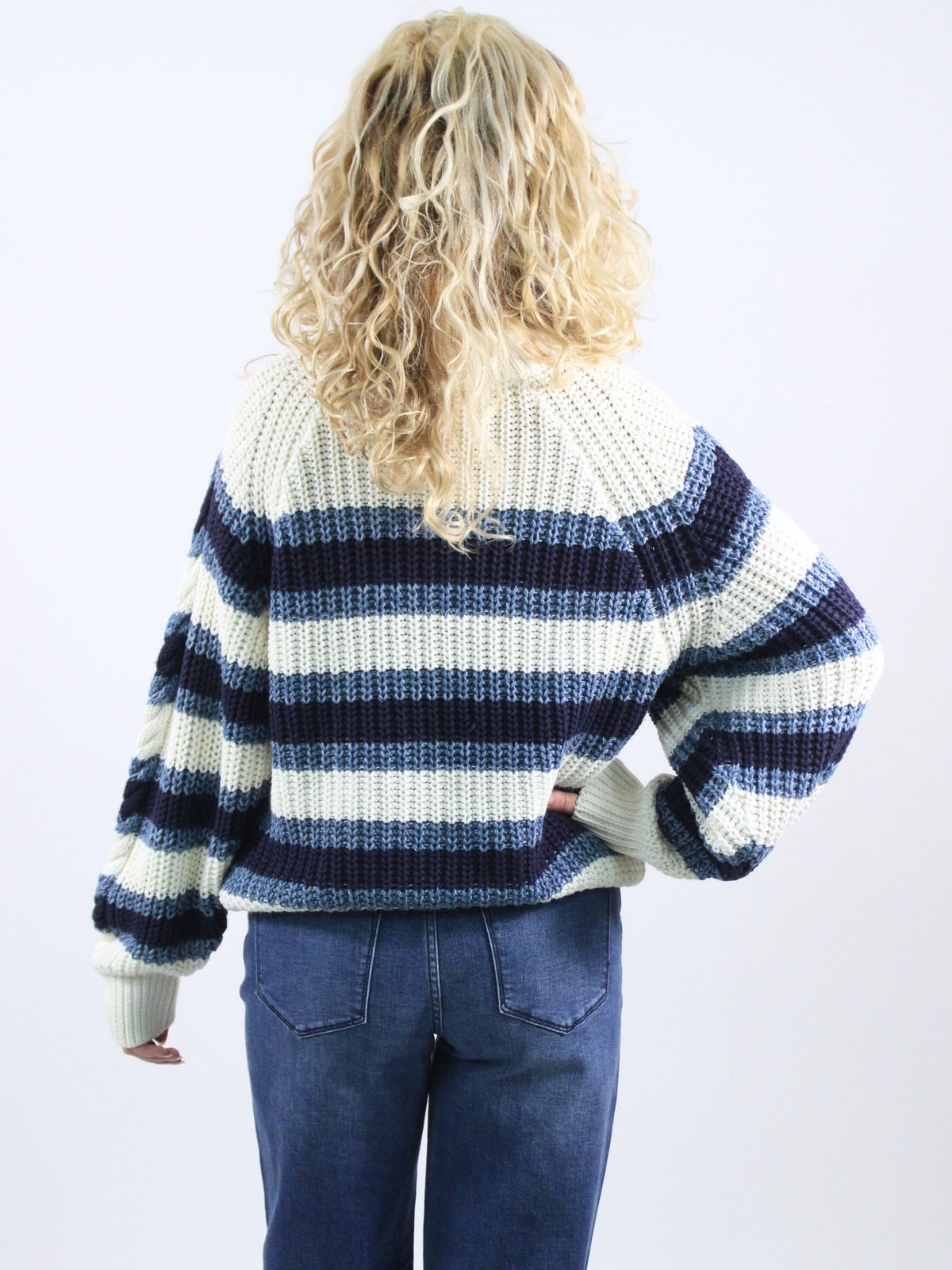 Person wearing a blue and white striped sweater on a plain background