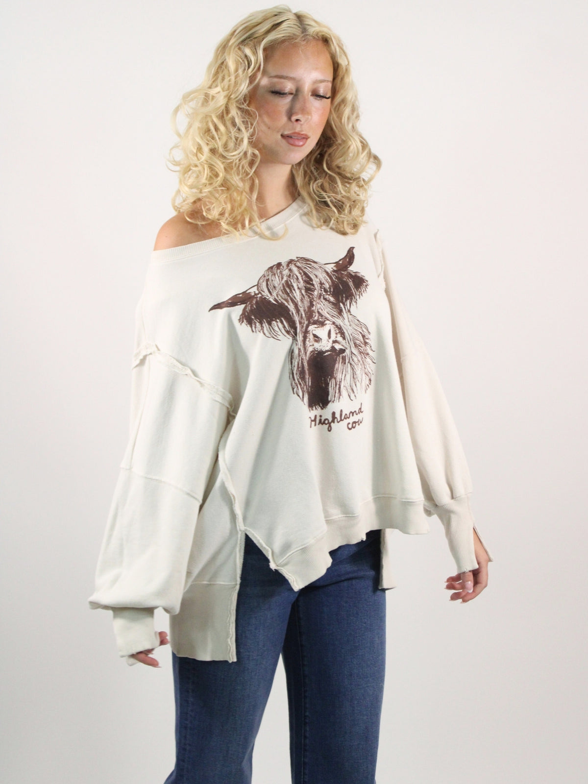 Woman wearing a white sweatshirt with a graphic design on a plain background