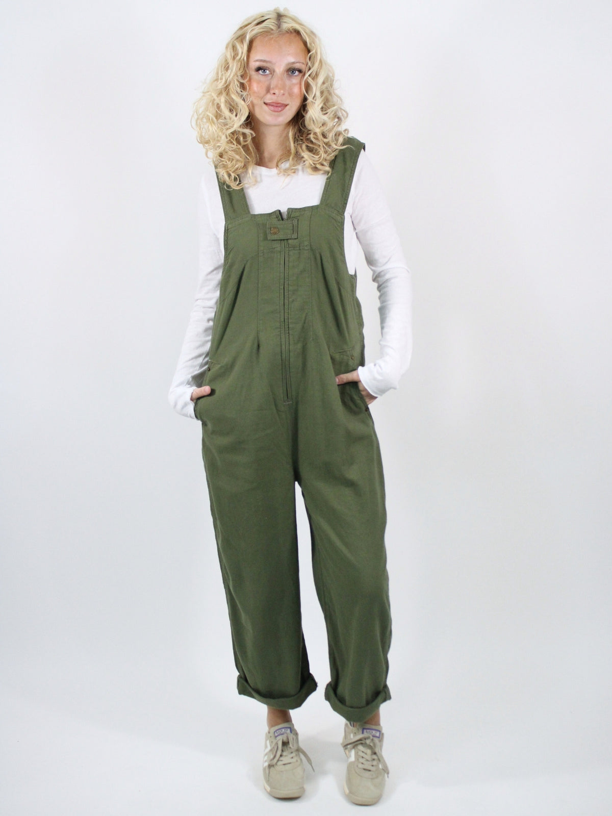 Person wearing green overalls and a white shirt on a white background