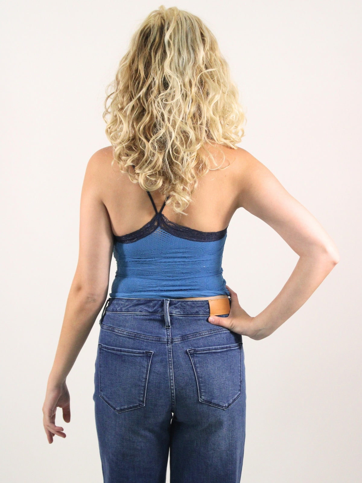 Person wearing a blue tank top and jeans on a white background