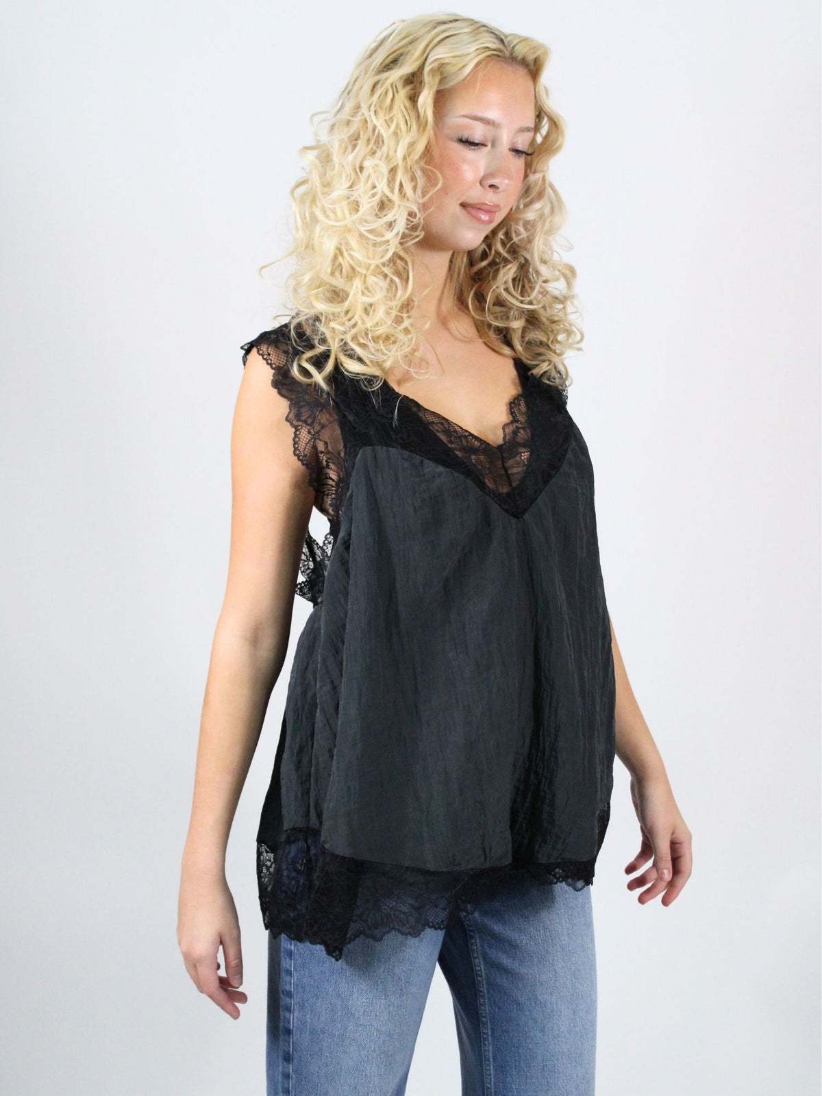 Woman wearing a black sleeveless top with lace details on a white background