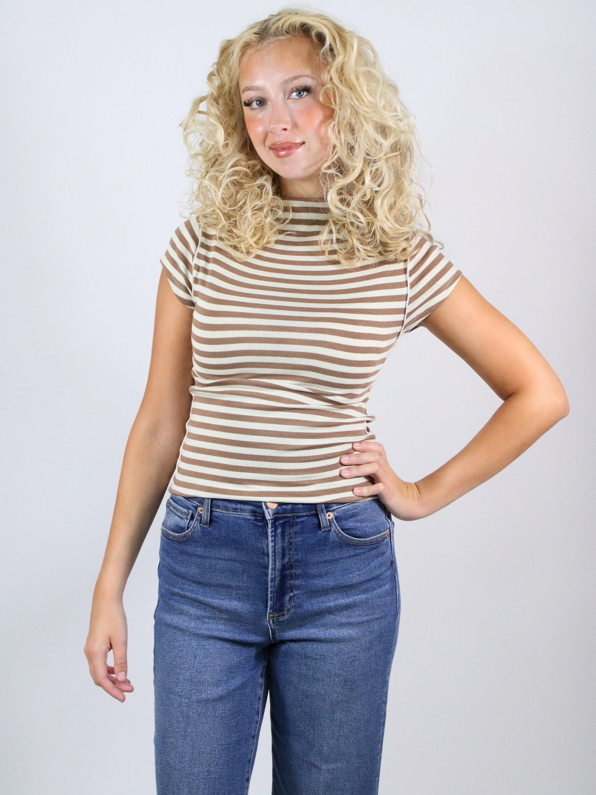 Woman wearing a striped shirt and jeans against a plain background
