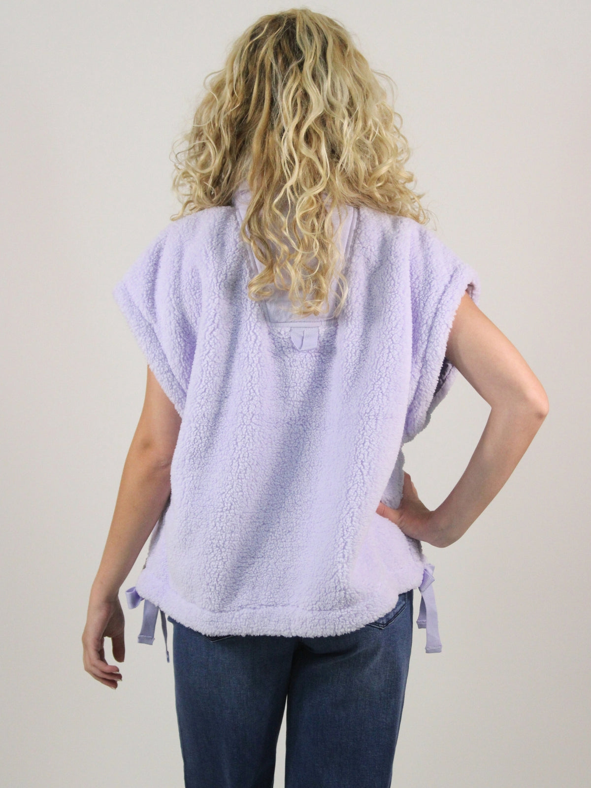 Person wearing a light purple towel vest over a white shirt on a plain background