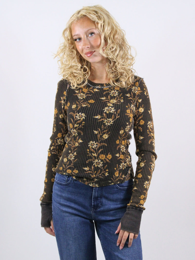 Woman wearing a black floral sweater and blue jeans on a white background