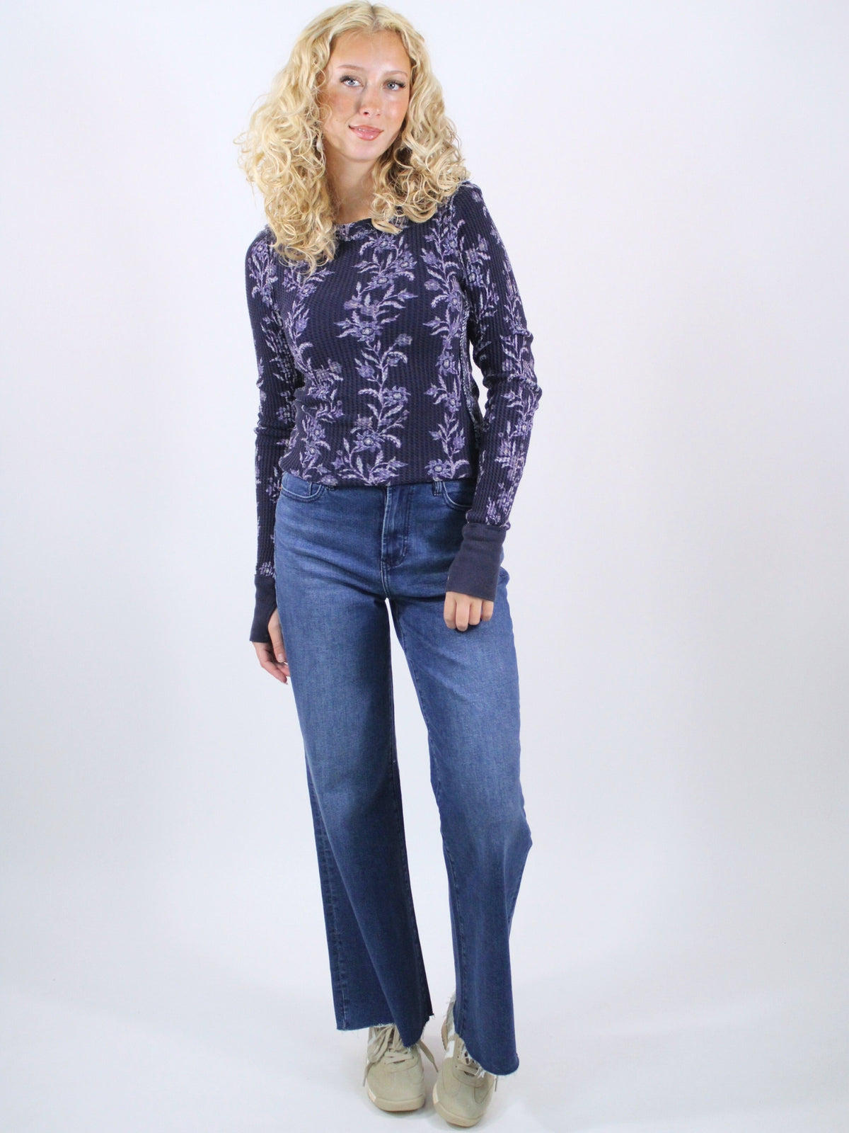 Woman wearing a dark floral shirt and blue jeans on a white background
