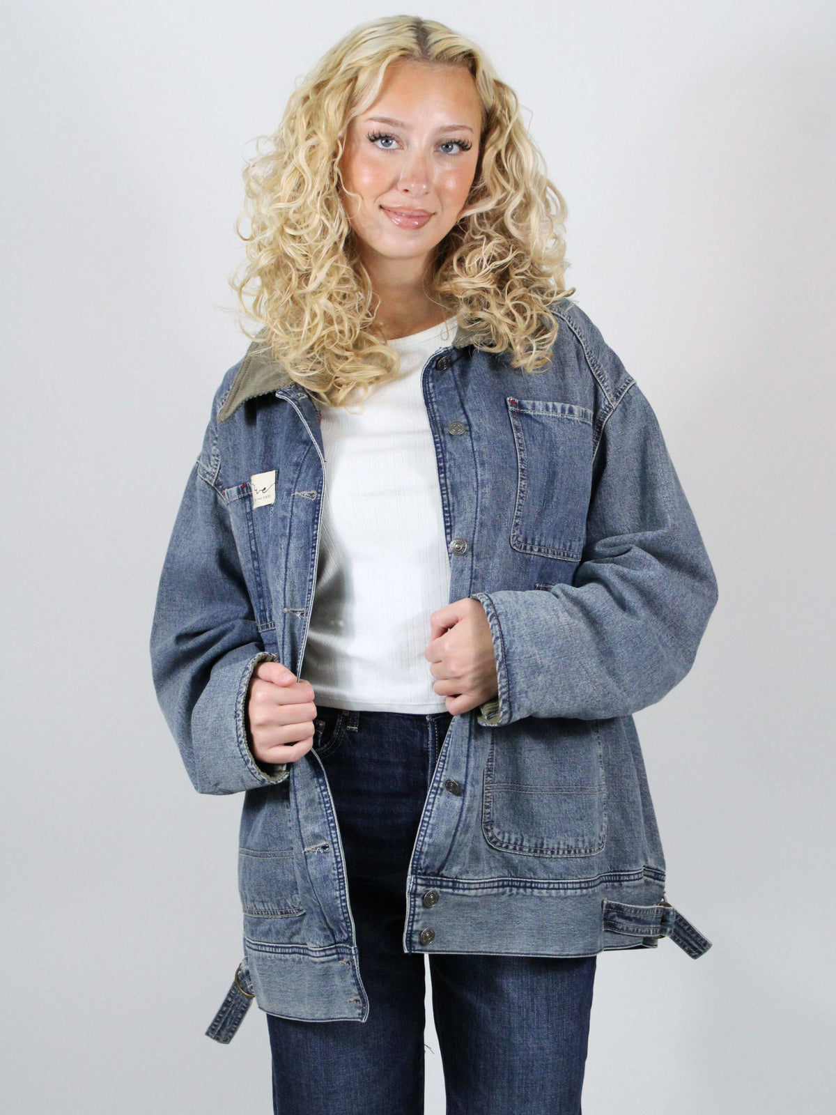 Woman wearing a denim jacket with a plain background
