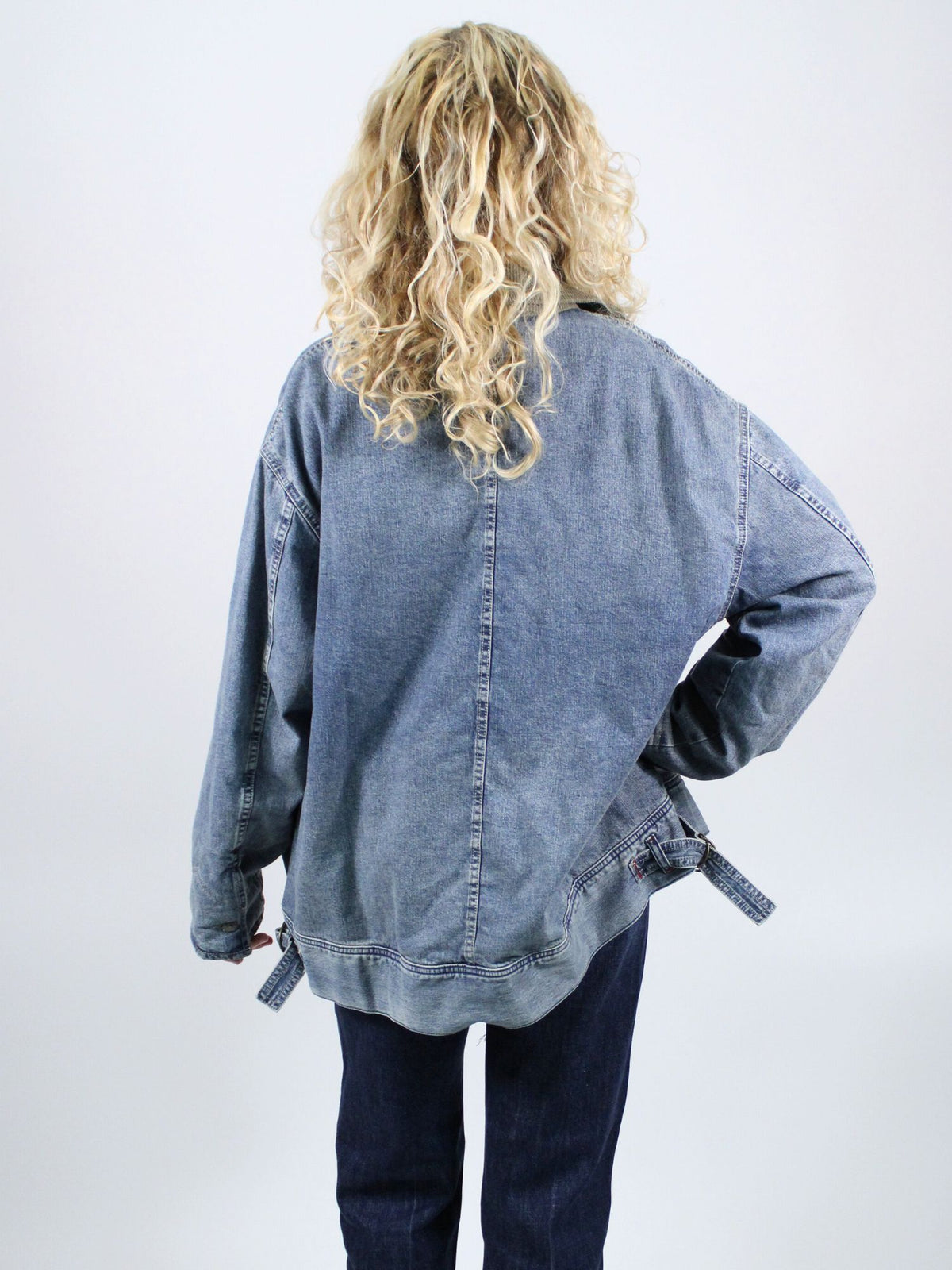 Person wearing a blue denim jacket from behind on a white background