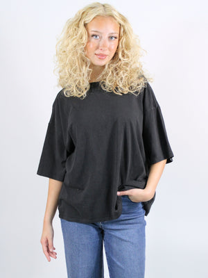 Woman wearing a black oversized top and blue jeans against a white background