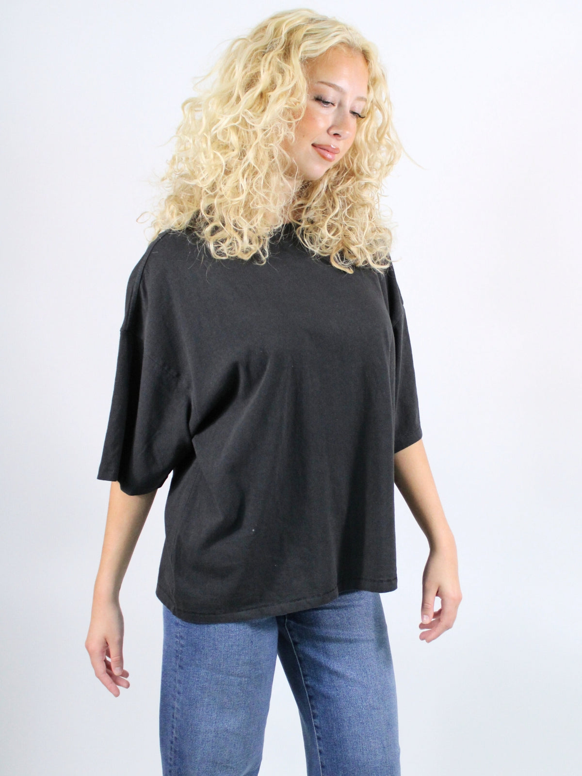 Woman wearing a black oversized shirt and blue jeans on a white background