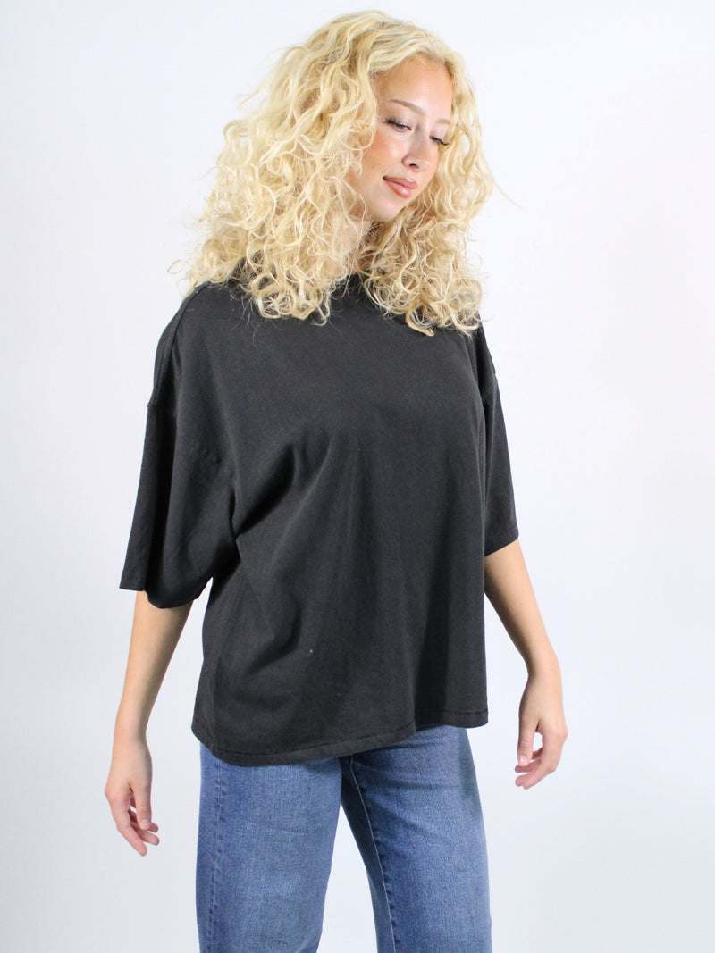 Woman wearing a black oversized shirt and blue jeans on a white background