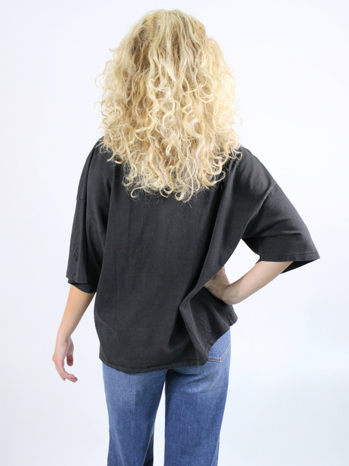 Person wearing a black oversized t-shirt and blue jeans on a white background