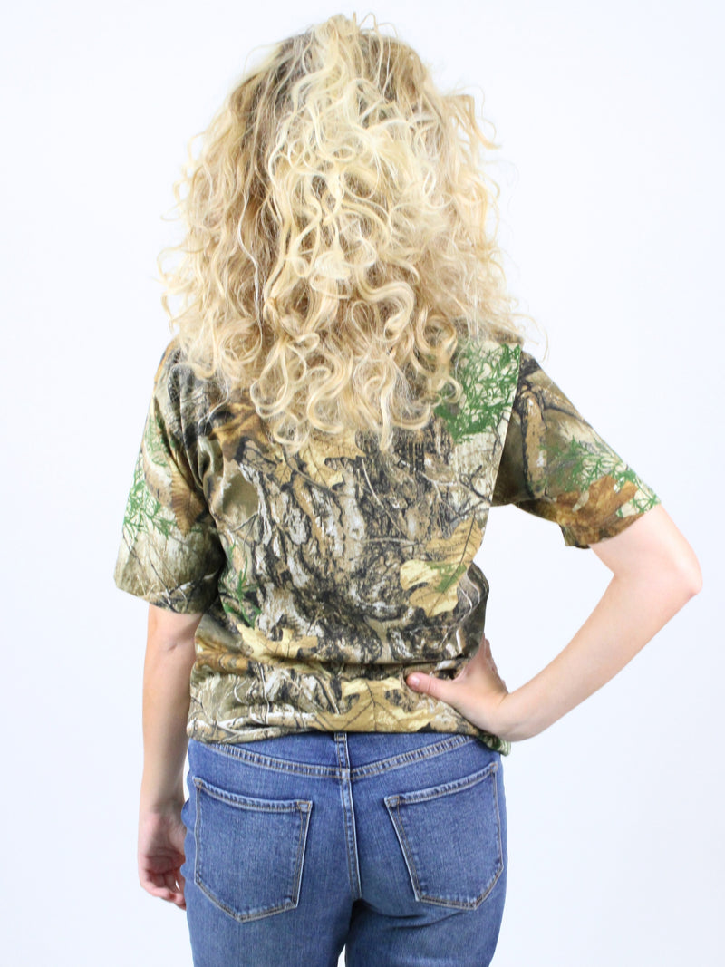 Person wearing a camouflage t-shirt and blue jeans on a white background